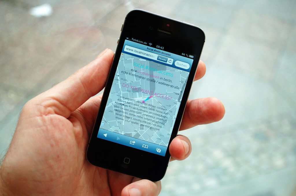 local.#non.access — a hand holding a phone showing the mobile site over a city map