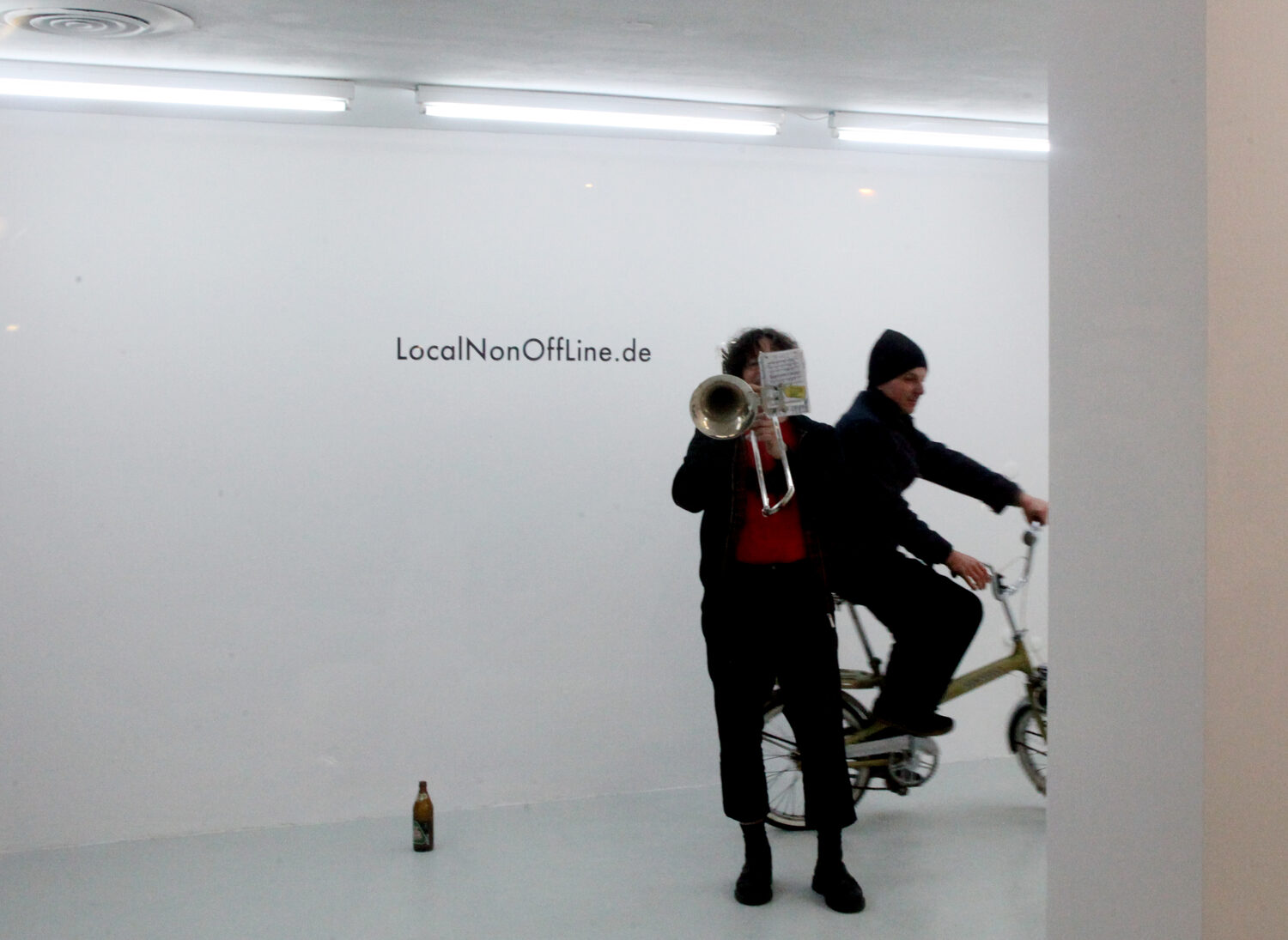LocalNonOffline — trombone and folding bike in front of the LocalNonOffLine.de wall lettering